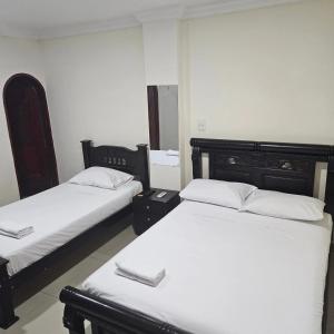 two beds in a room with white sheets at Hotel Barranquilla Inn in Barranquilla