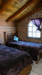 2 camas en una habitación con una pared de ladrillo en Hotel Real de San Antonio, en Estanzuela