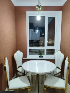 ein Esszimmer mit einem Tisch, Stühlen und einem Fenster in der Unterkunft Аппартаменты с гостиничным обслуживанием на набережной in Kirovo