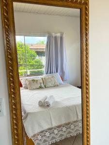 a mirror reflecting a bed in a room with a window at Espaço caraguatá in Florianópolis