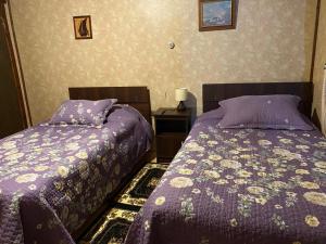 2 camas en un dormitorio con edredón púrpura en La posada del turista, en llifen