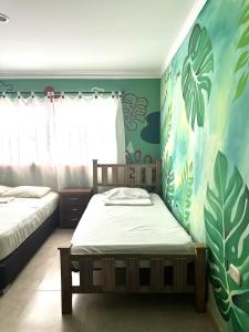 1 dormitorio con 2 camas individuales y papel pintado tropical en Hostal Casa Macondo, en Santa Marta