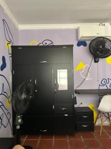 Hostal Casa Macondo في سانتا مارتا: خزانة سوداء مع مروحة في الغرفة