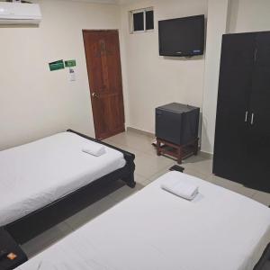 Cette chambre comprend 2 lits, une télévision et une porte. dans l'établissement Hotel Barranquilla Inn, à Barranquilla
