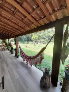 a hammock on a porch with a view of a field at Recanto Alto da Serra 