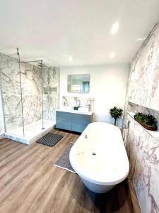 ein Badezimmer mit einer weißen Badewanne und einer Dusche in der Unterkunft Historic Charm: *Perfect For Group Getaways* in Trowbridge