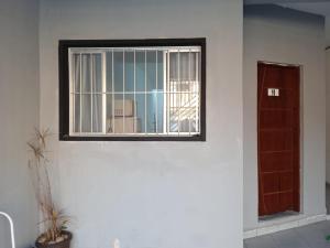 ein Fenster in einer weißen Wand mit einer Tür in der Unterkunft Flat Itavuvu in Sorocaba