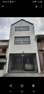 a white building with a gate in front of it at Flat Itavuvu in Sorocaba