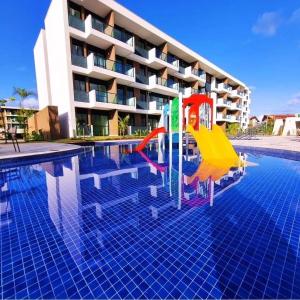 a pool with a slide in front of a building at Muro Alto-Porto de Galinhas Flat Makia 104D in Ipojuca