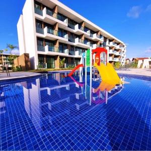 una piscina con un tobogán frente a un edificio en Muro Alto-Porto de Galinhas Flat Makia 104D en Ipojuca