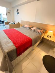 a bedroom with a large bed with a red blanket at Muro Alto-Porto de Galinhas Flat Makia 104D in Ipojuca