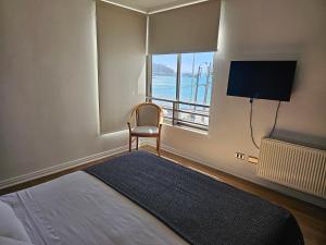 a bedroom with a bed and a chair and a window at Espectacular Bahía Bonita depto 22 in Concón