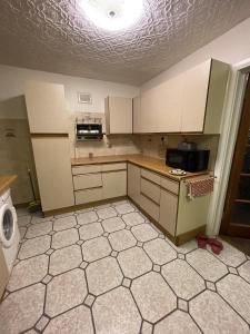 a kitchen with white cabinets and a tiled floor at Inviting 2-Bed House in Birmingham in Birmingham