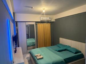 1 dormitorio con cama verde y espejo en Jasmin Park Apartemen By Fix's Room, en Kedungbadak