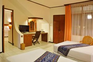 a hotel room with two beds and a desk at Puri Naga Beachfront Cottages in Legian