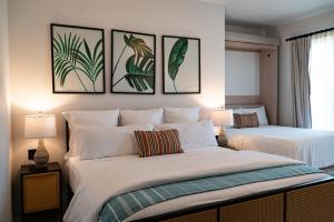 2 Betten in einem Schlafzimmer mit 3 Bildern an der Wand in der Unterkunft Flamboyan Hotel & Residences in San José del Cabo