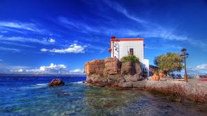 a building on a rock in the water at Pension Niki in Skála Sykaminéas