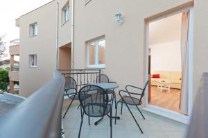 a balcony with chairs and a table and a living room at Apartments Branka in Podgora
