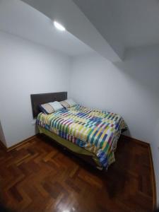 Bett in einem weißen Zimmer mit Holzboden in der Unterkunft Edificio parque residencial in Lima