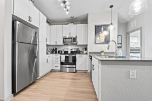 a kitchen with white cabinets and a stainless steel refrigerator at Downtown St Pete 2 Bed Near Tropicana Field WIth Free Parking in St. Petersburg