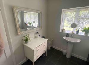 Baño blanco con lavabo y espejo en Ladram on Haroldslea en Horley