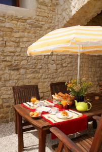 a wooden table with an umbrella and food on it at Chez Catharina Oldtimer B&B in Levoncourt