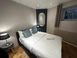 1 dormitorio con 1 cama grande con sábanas blancas y almohadas azules en Doric apartment en Londres