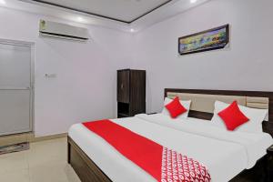 a bedroom with a large bed with red pillows at Collection O Hotel Prime A-One Inn Near Chaudhary Charan Singh International Airport in Bijnaur