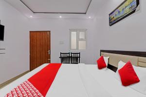 a bedroom with a large white bed with red pillows at Collection O Hotel Prime A-One Inn Near Chaudhary Charan Singh International Airport in Bijnaur