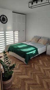 a bedroom with a bed with a green blanket at Apartamenty Urban Concept in Zamość