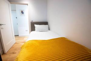 a bedroom with a bed with a yellow blanket at Cosy 2 Bed Apartment, East Croydon in Croydon