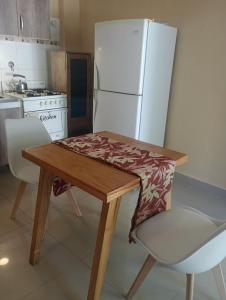 a kitchen with a wooden table and a white refrigerator at AlquiloenNeuquen in Neuquén