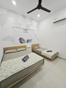 two beds in a room with a ceiling fan at Air-home No 28 Simpang near Aulong Econsave, 3BR, 7pax, Netflix in Simpang