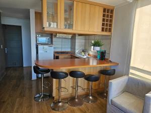 a kitchen with a wooden counter and bar stools at Espectacular Bahía Bonita depto 41 in Concón