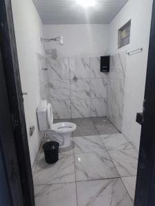 a white bathroom with a toilet and a shower at Casa aconchego com piscina in Guaratuba