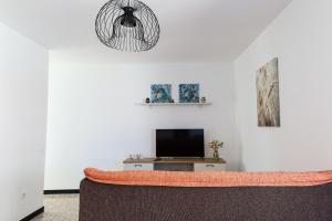 a living room with a couch and a tv at Los Arenales Agaete in Agaete