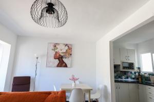 a white living room with a table and a chandelier at Los Arenales Agaete in Agaete