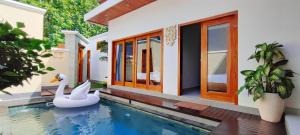 a swimming pool in front of a house with a swan at Villa Panda in Lovina