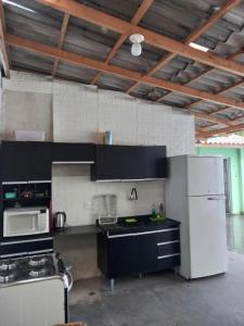 a kitchen with black cabinets and a white refrigerator at Casa aconchego com piscina in Guaratuba