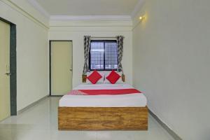 a bedroom with a bed with red pillows and a window at Flagship Sai Executive Lodging Near Fun Time Multiplex in Pune