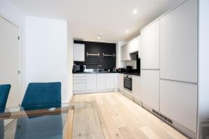 cocina con armarios blancos y mesa de cristal en Luxury Apartment by Ocean Village Marina en Southampton