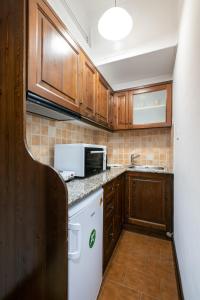 a small kitchen with wooden cabinets and a microwave at Afrodite Hotel Apartments in Myrina