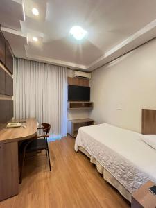 1 dormitorio con cama, escritorio y mesa en Regente Hotel, en Pato Branco