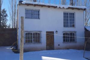 a white house with a door in the snow at Hermosa Cabaña Duplex Malargüe. in Malargüe