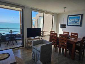 a living room with a dining room table and a television at Espectacular Bahía Bonita depto 43 in Concón