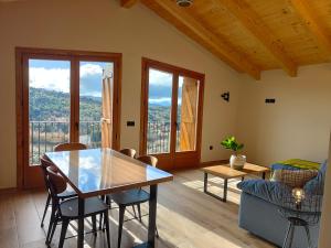 a dining room with a table and chairs and windows at LAS BORDAS DE MIQUELET in Viacamp