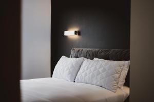 a bed with white sheets and a light on the wall at Luxury Apartment by Ocean Village Marina in Southampton