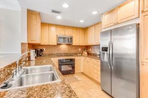 a kitchen with wooden cabinets and a stainless steel refrigerator at Portofino Island P2-905 in Pensacola Beach