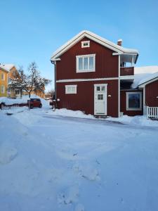 une maison rouge avec une porte blanche dans la neige dans l'établissement Kiruna accommodation Gustaf wikmansgatan 6b (6 pers appartment), à Kiruna