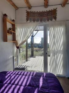 a bedroom with a purple bed and a sliding glass door at Mandalei, Refugio De Mar in Las Grutas +30 photos